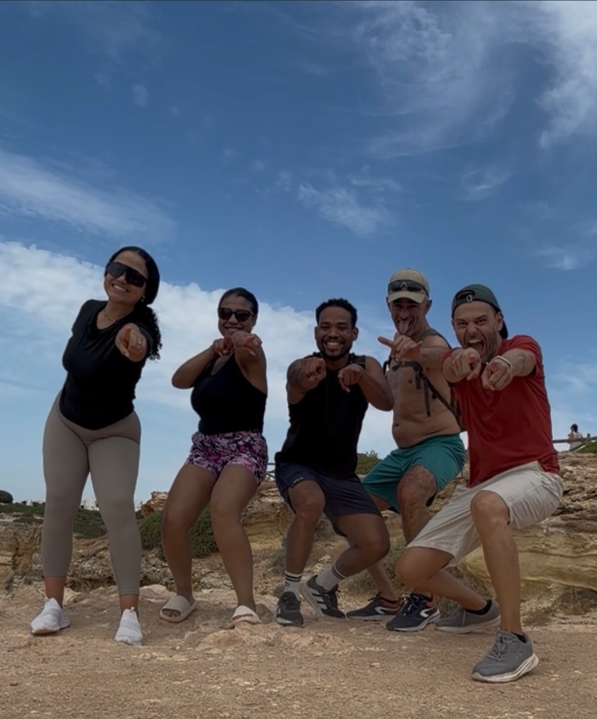Cinco participantes do Mindwalk apontam para a câmara, a rir, no alto de uma falésia